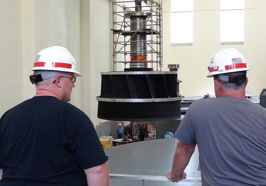 Several Corps of Engineers employees watch as work crews lift the turbine runner out of hydropower unit two in the power house at Center Hill Dam Oct. 7, 2015. The U.S. Army Corps of Engineers Nashville District is rehabbing all three units at the dam. (USACE photo by Leon Roberts)